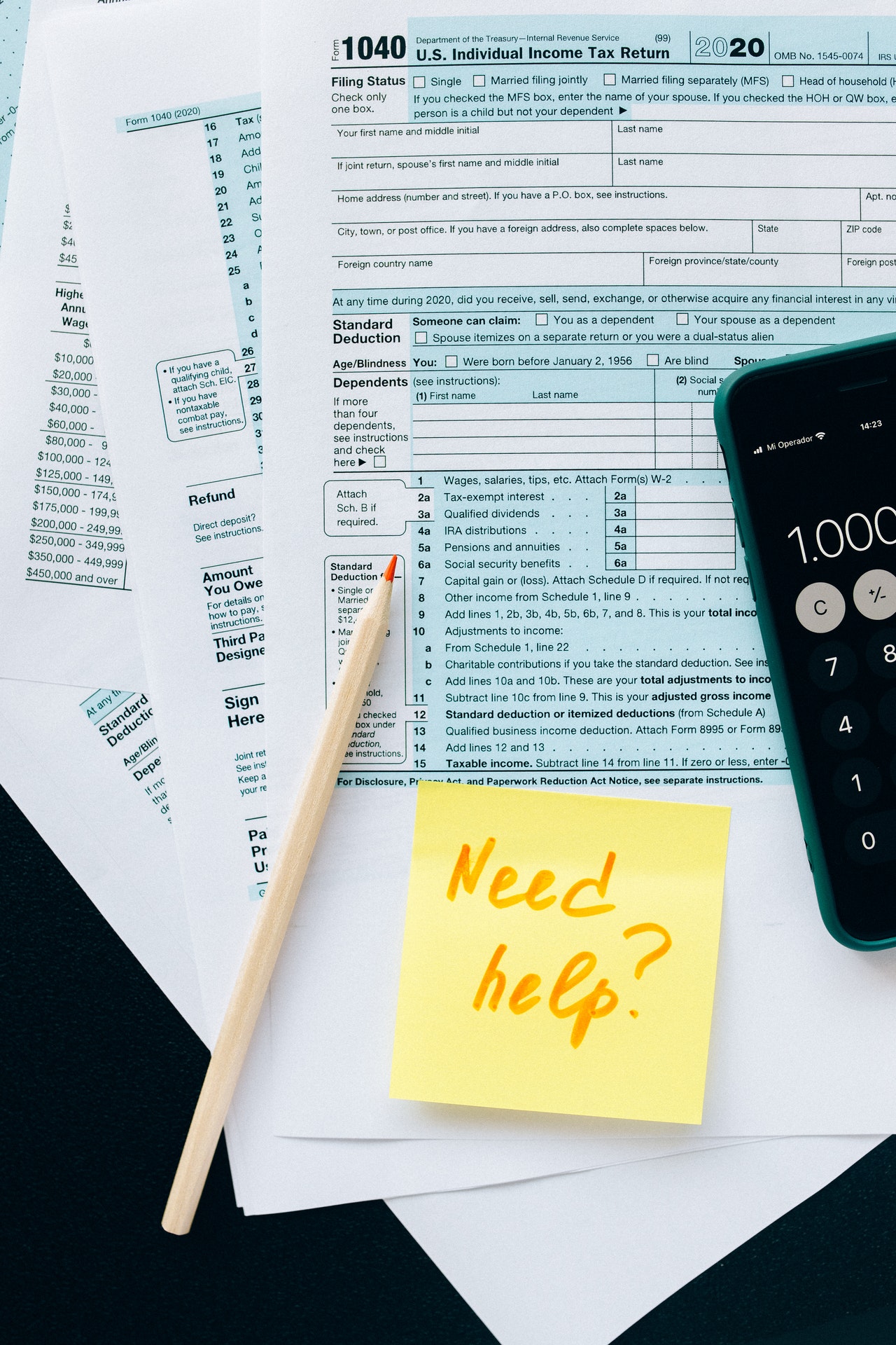 Tax documents, calculator, and pen with yellow post-it reading "Need help?"