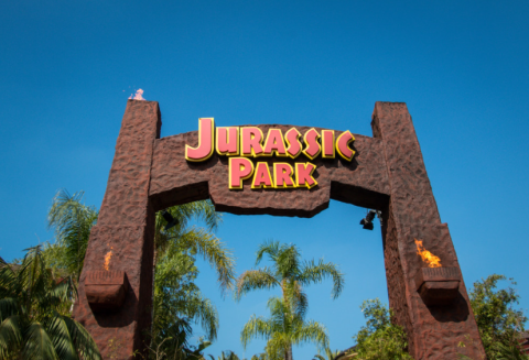 A big sign on the large gate entrance to Jurassic Park. 