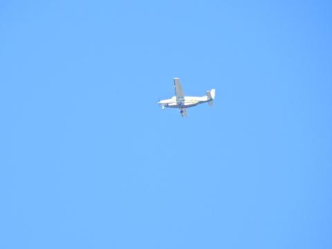 Small plane flying with blue sky background.
