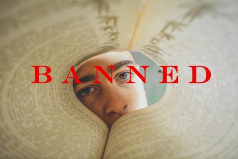 Patron looking through the pages of a curled book that has the word "Banned" in front of it