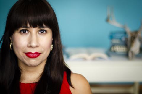 Author Erika Sanchez appears in a red dress against a blurred background