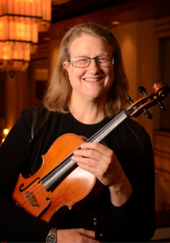 Image of Deborah Dakin smiling and holding the viola.