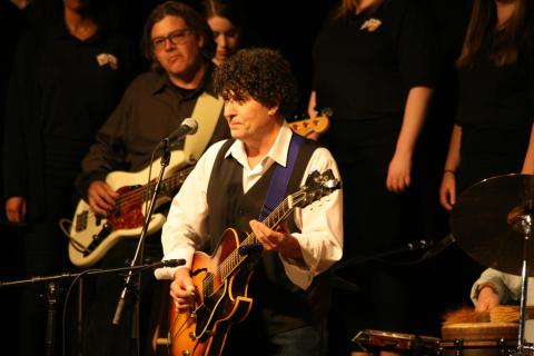 Image of Chris Vallillo playing a guitar on stage.