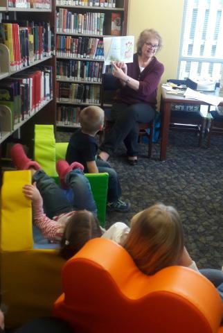 Photo of children listening to librarian telling a story at the Southwest Library. 