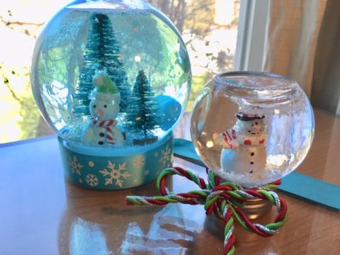 Snowman and bottle brush tree snow globe near window