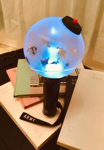 Photo of sea green, pink and white BTS albums and spherical glow stick.