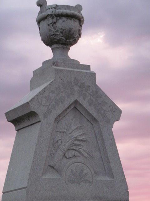 close up of monument at riverside cemetery with sundown sky behind stone 