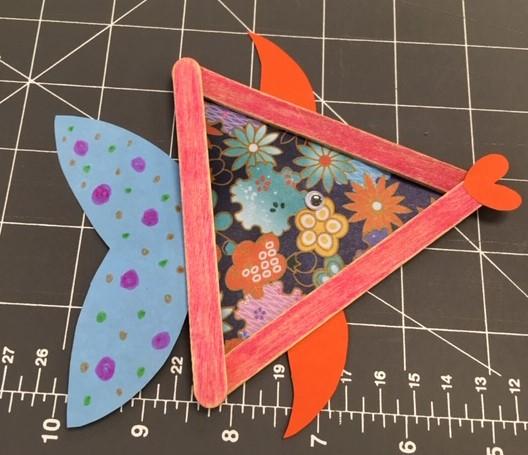 Craft fish made with 3 popsicle sticks and patterned paper fins.