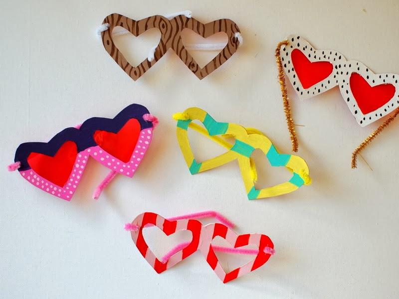 Several pairs of heart-shaped glasses made of cardboard and decorated with markers.